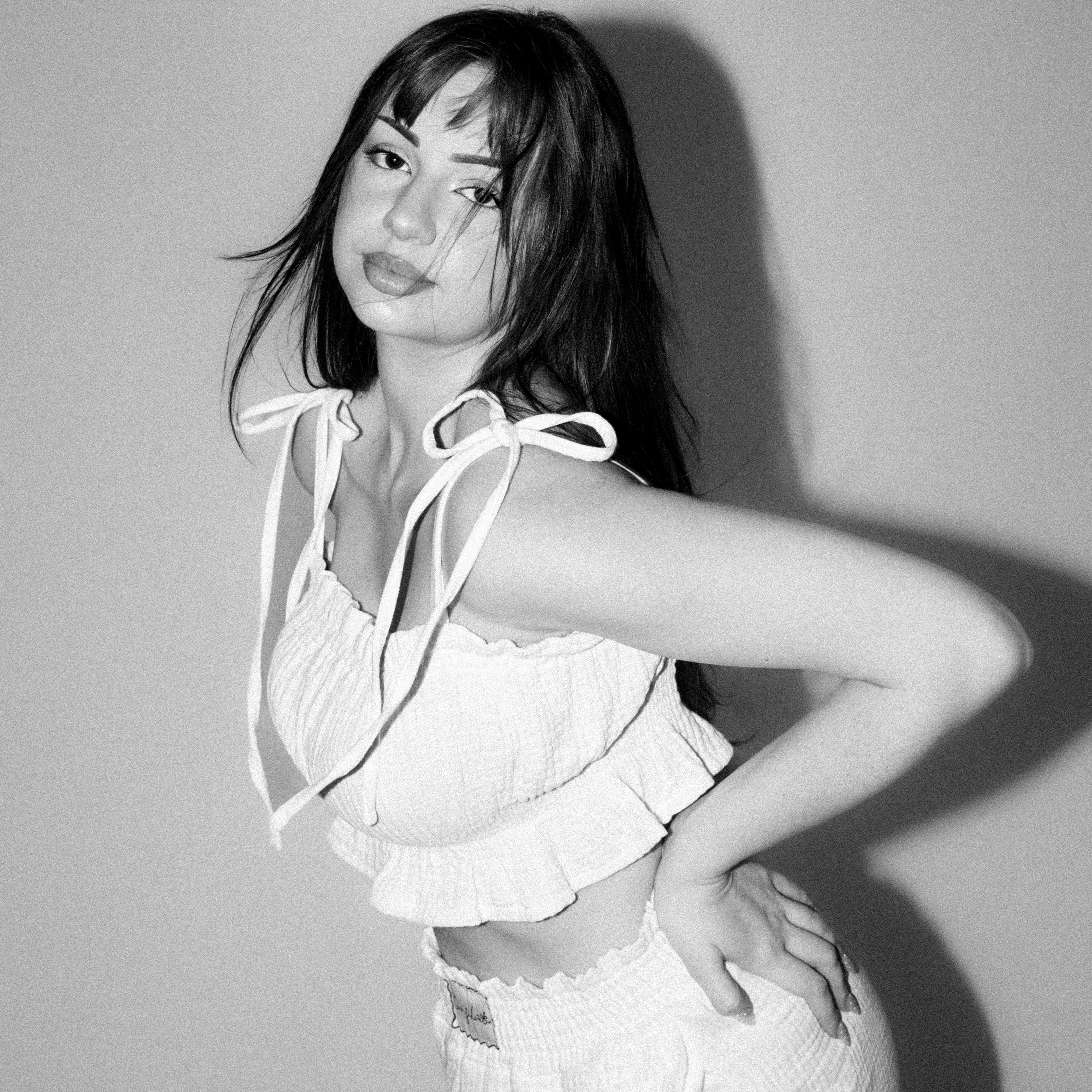 Nela Valentiina v bílém mušelínovém setu Luna Comfident Studio, top na ramínka se zavazováním a šortky s elastickým pasem, černobílá lifestyle fotografie