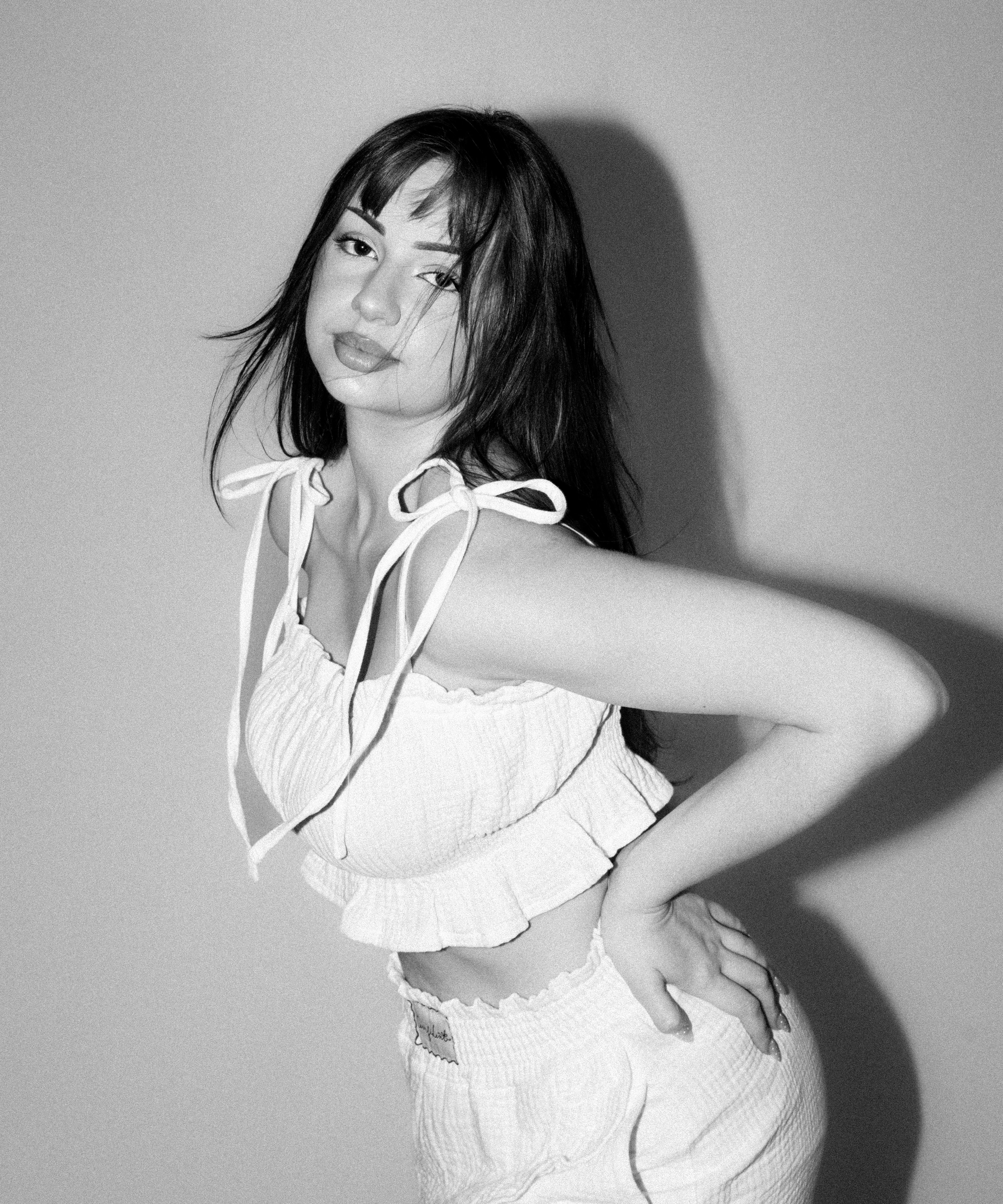 Nela Valentiina v bílém mušelínovém setu Luna Comfident Studio, top na ramínka se zavazováním a šortky s elastickým pasem, černobílá lifestyle fotografie
